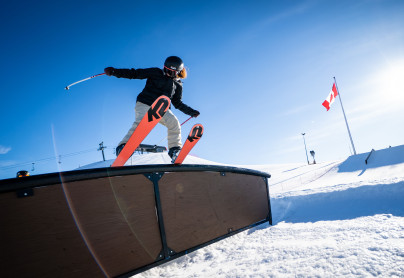 Female skier at WinSport doing freestyle skiing trick on rail