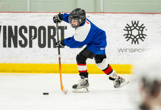 Young hockey camper passing the puck during a summer camp