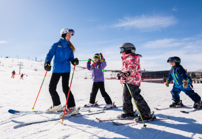 WinSport Instructor with a group of children learning how to ski on snow